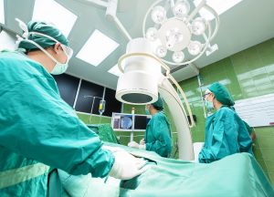 Chirurgen in grünen Operationskitteln und Schutzmasken arbeiten in einem modernen Operationssaal mit hochtechnologischen medizinischen Geräten, was die fortgeschrittene medizinische Versorgung im Gesundheitswesen und Versicherung der Niederlande unterstreicht.